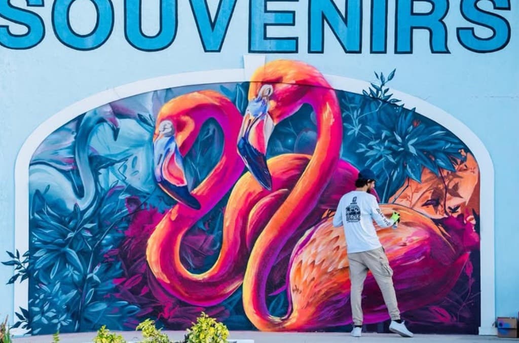 Bulk Styles working on a flamingos mural with tropical foliage